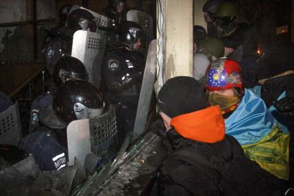 Протестующие штурмуют Украинский дом. На снимке: протестующие у входа в здание ведут переговоры с бойцом специального подразделения `Беркут`.