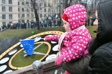 Женщина держит ребенка который держит флг Евросоюза на площади Независимости в Киеве.