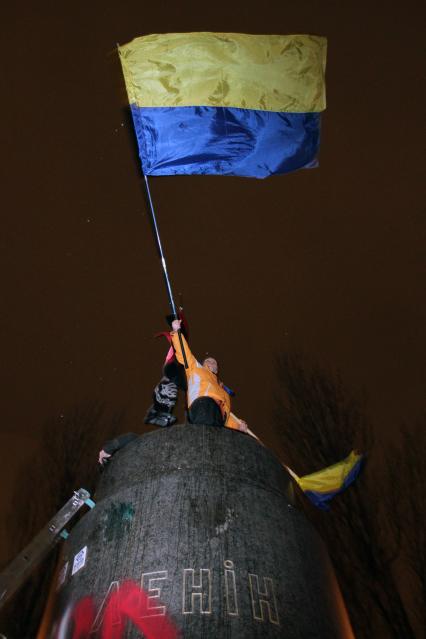 Протестующий с украинским флагом на постаменте памятника В. Ленину.