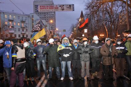 Толпа протестующих перекрывает автомобильное движение на улице в Киеве.