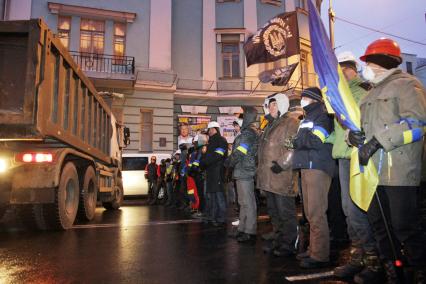 Толпа протестующих перекрывает автомобильное движение на улице в Киеве.