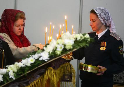 Женщина в погонах на фоне горящих свечей.