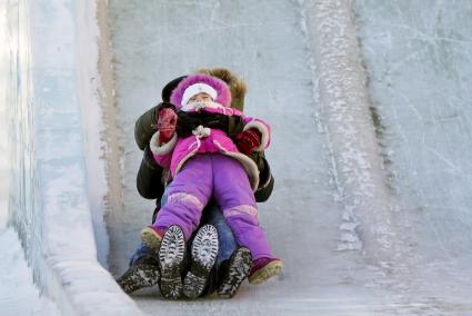 Дети катаются с ледяной горки.