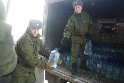 Армия помогает жителям города с подвозом воды. На снимке: солдаты разгружают грузовой автомобиль который привез питьевую воду в пластиковых бутылках.