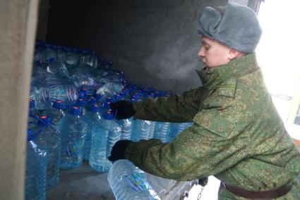 Армия помогает жителям города с подвозом воды. На снимке: солдат разгружает грузовой автомобиль который привез питьевую воду в пластиковых бутылках.