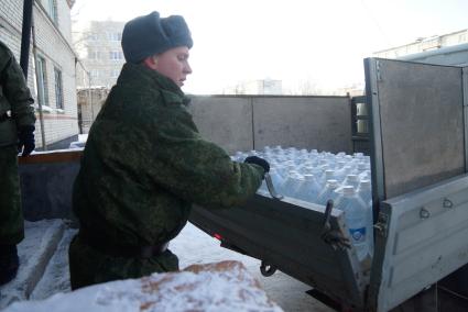 Армия помогает жителям города с подвозом воды. На снимке: солдат открывает борт грузового автомобиля который привез питьевую воду в пластиковых бутылках.