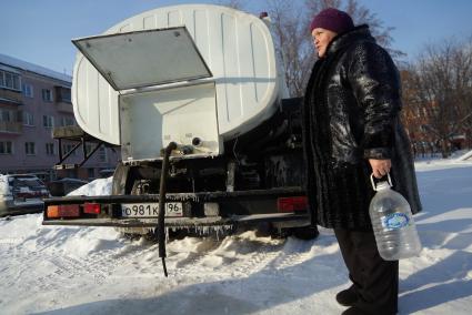 Женщина с пустой бутылкой у водовоза.