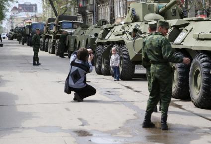 Перед Парадом Победы военная техника дислоцируется на улицах города. На снимке: мужчина фотографирует своего ребенка на фоне военной техники.