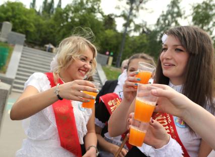 Школьники празднуют последний звонок. На снимке: девушки отмечают выпускной с соком в руках.