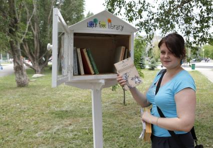 Девушка у бокс для обмена книгами `Свободная библиотека`.