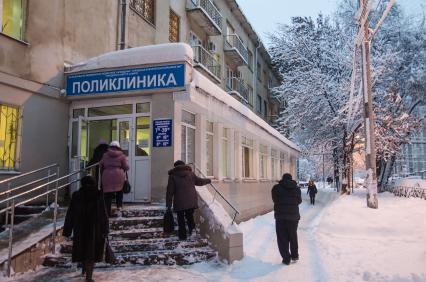 Люди заходят в городскую поликлинику.