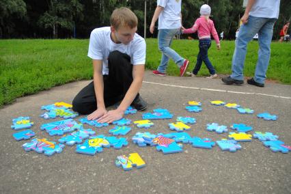 Подросток собирает пазл на асфальте.