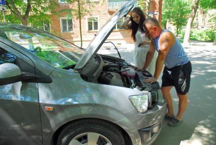 У девушки сломался автомобиль, мужчина пытается ей помочь.