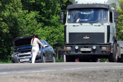 У девушки сломался автомобиль, она голосует в поисках помощи.