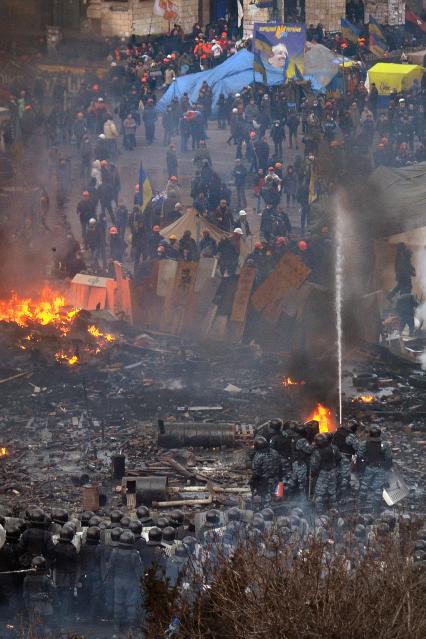 Сотрудники внутренних войск поливают сторонников оппозиции водой из брандспойта.