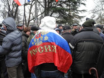 Митинг у здания парламента Крыма в Симферополе. Человек с российским флагом на митинге.