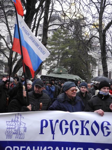 Митинг у здания парламента Крыма в Симферополе. Митингующие с российским флагом и плакатом на фоне памятника танку `т-34`.