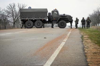 Блок-пост на дороге ввиде грузового автомобиля посередение дороги контролируемый военными.