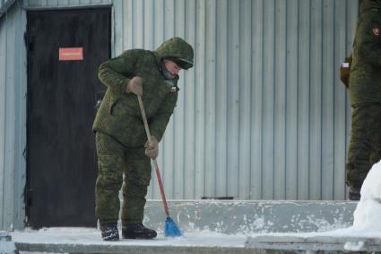 Полигон Уральского учебного центра под Екатеринбургом. Солдат убирает снег метлой.