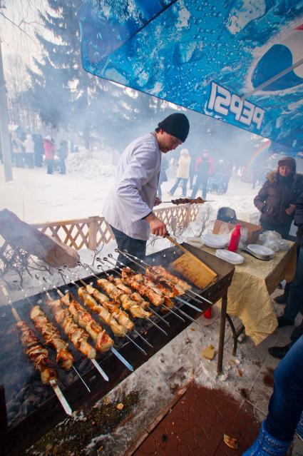 Мужчина жарит шашлыки.