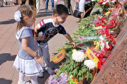 Дети кладут цветы к мемориалу.