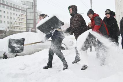 Молодежь убирает снег с улиц после сильного снегопада.