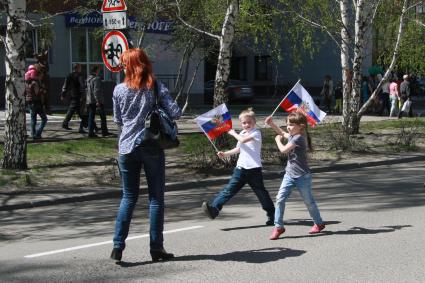 Дети с российскими флагами на улице во время празднования Дня Победы.