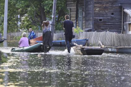 Люди с лодками ходят по улице поселка.