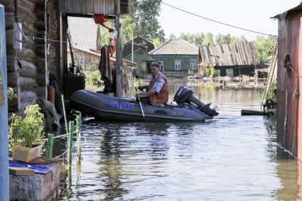 Мужчина на моторной надувной лодке около своего дома.