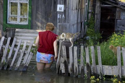 Женщина с кошкой около затопленного водой учатска.