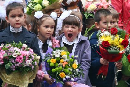 Первое сентября. Первоклассники. Зевающая девочка на утренней школьной линейке.