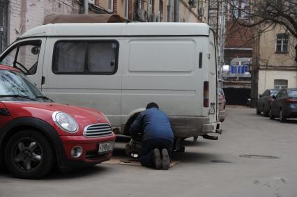 Мужчина ремонтирует колесо автомобиля.