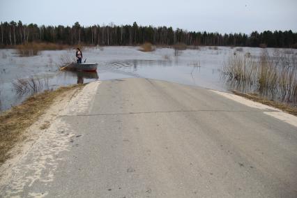 Паводок на реке Уста Уренского района Нижегородской области. Затопленная автомобильная дорога. Девушка в весельной лодке на река во время паводка.