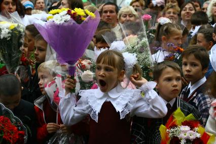 Зевающая первоклассница на школьной линейке в день знаний.