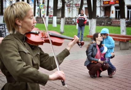 Женщина с ребенком слушают игру на скрипке.
