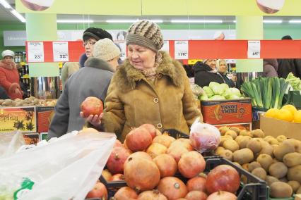 Пенсионер в продуктовом супермаркете выбирает продукты.