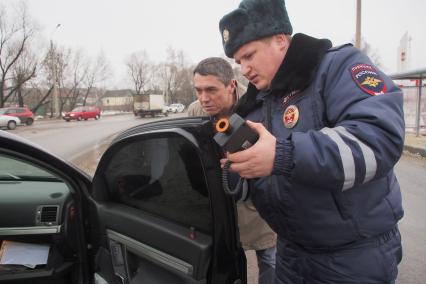 Сотрудник ДПС ГИБДД замеряет тонировку стекол автомобиля.