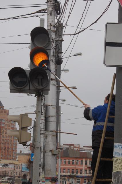 Рабочий на улице моет светофор на улице.