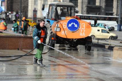 Работники службы ЖКХ. На снимке: мужчина поливает водой брусчатку
