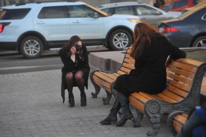 Девушки фотографируются в парке.