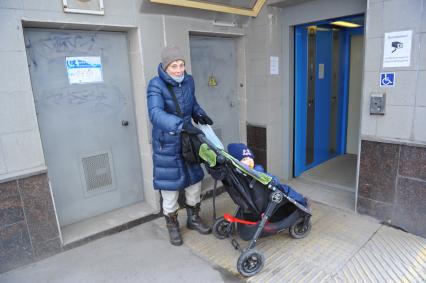 Ленинградское шоссе. На снимке: женщина с ребенком в детской коляске у лифта для людей с ограниченными возможностями в подземном переходе.