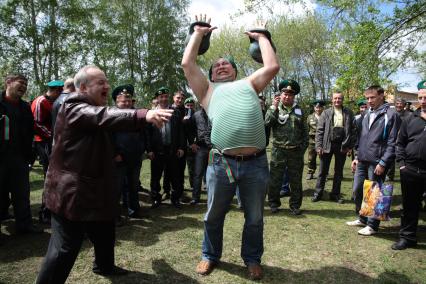 День пограничника. Мужчина в тельняшке пограничника поднимает гири.