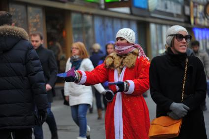 Девушка в костюме Деда Мороза раздает флаерсы.