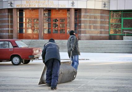 Рабочие волокут чугунную ванну.