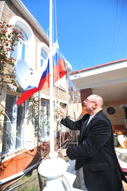 Севастополь. На снимке: крымчанин Вячеслав Николаев поднимает российский флаг, установленный на территории его дома.