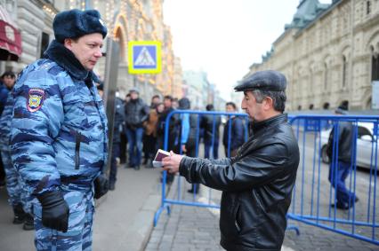 Сотрудник полиции проверяет документы у мигранта.