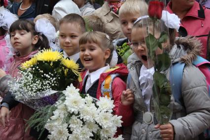 Первоклассники в день знаний на школьной линейке с букетами цветов..