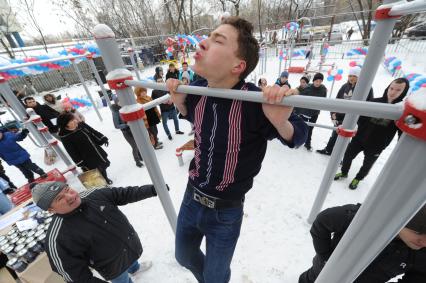 На спортивной площадке в Савеловском районе прошел конкурс `Подтянись больше главы управы`. На снимке: молодой человек подтягивается на турнике.