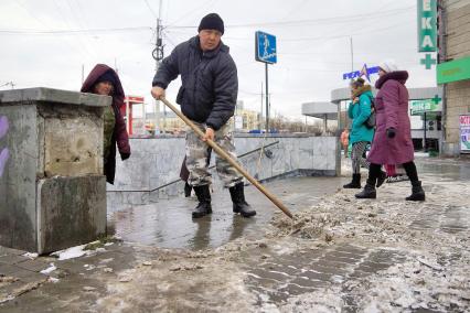 Дворник очищает улицу от льда и снега.