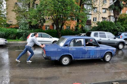 Наводнение в Сочи. Мужчина толкает заглохший автомобиль.